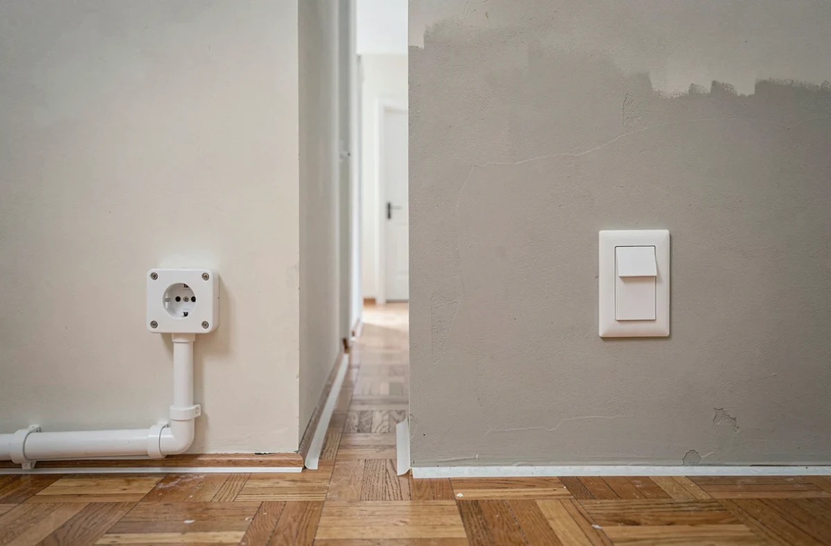 Comparaison entre prise sur goulotte et prise encastrée dans un couloir de maison en rénovation